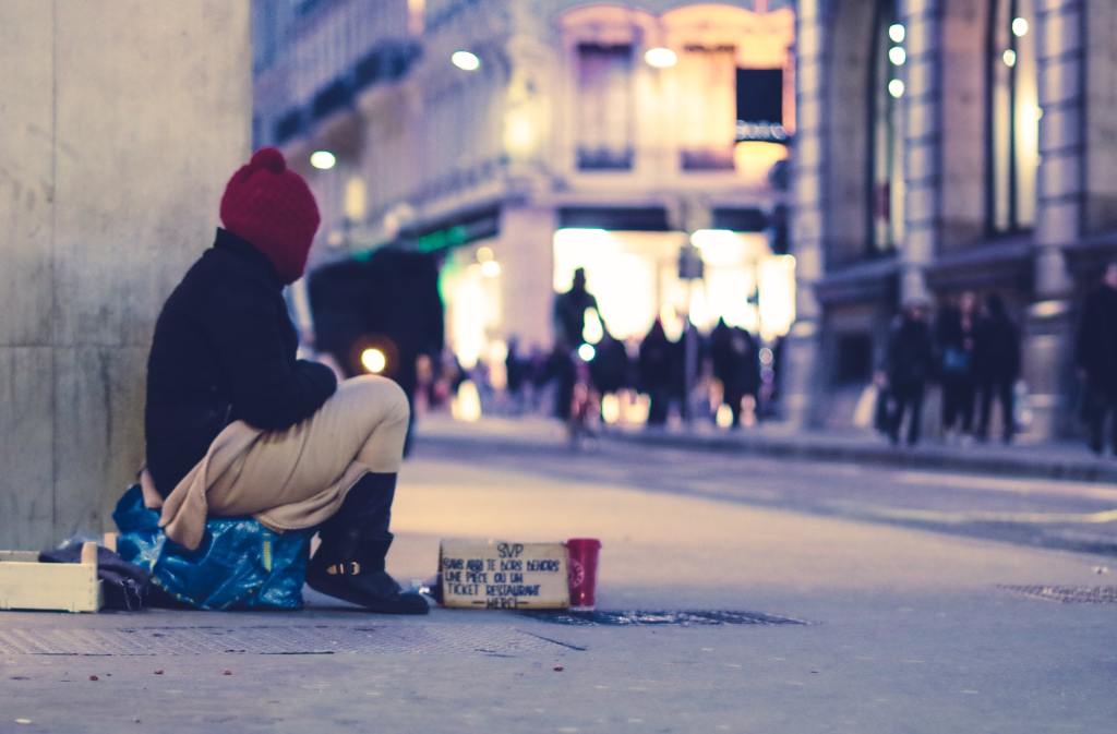 A person sits on a bag, observing a busy city street 